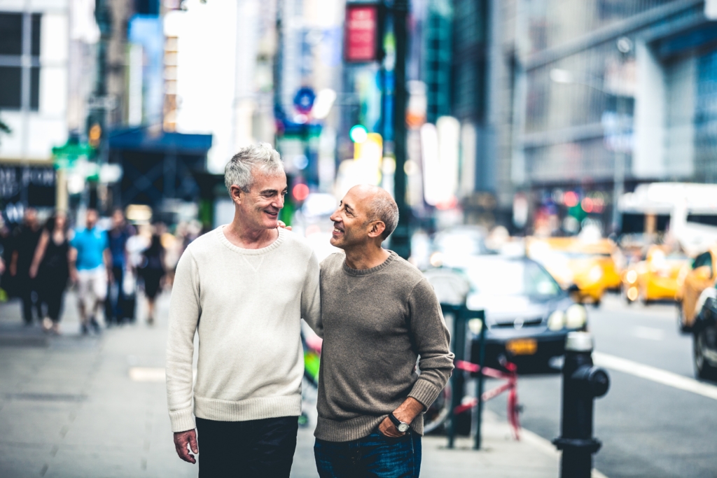 Gay couple walking in New York downtown. They are happy visiting the popular spots of the city.