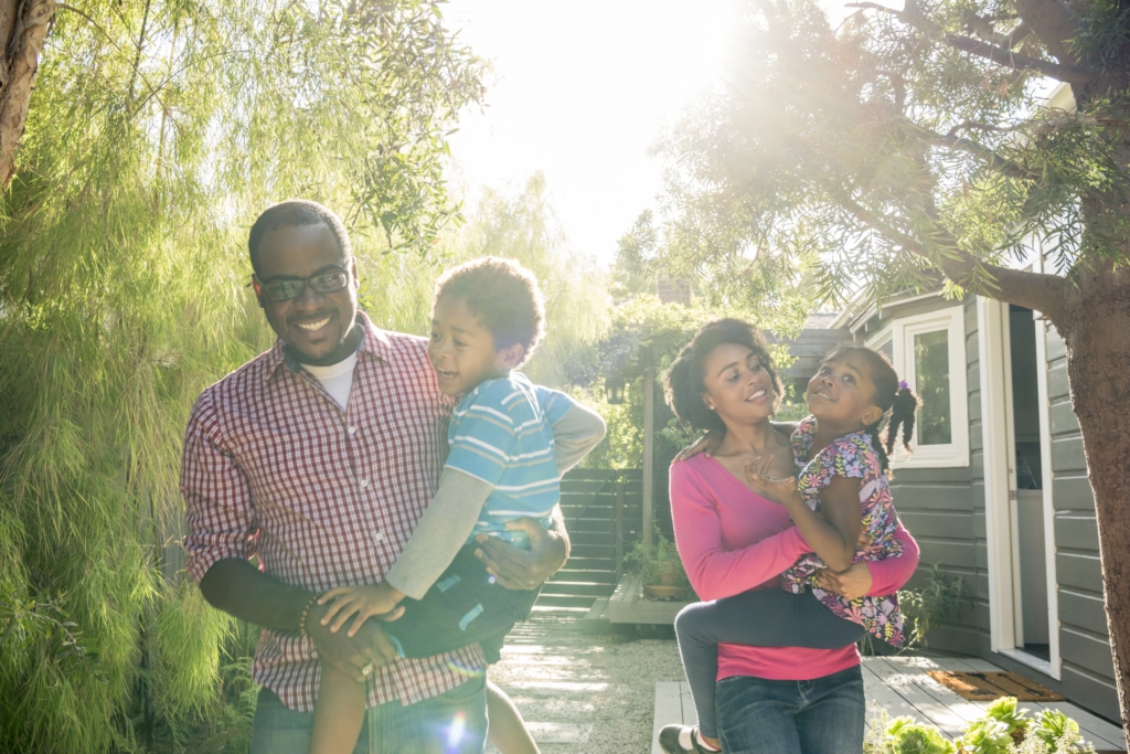 Cheerful parents holding son and daughter in the sunlight, smiling