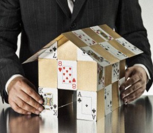 Businessman holding door open to gold house of cards